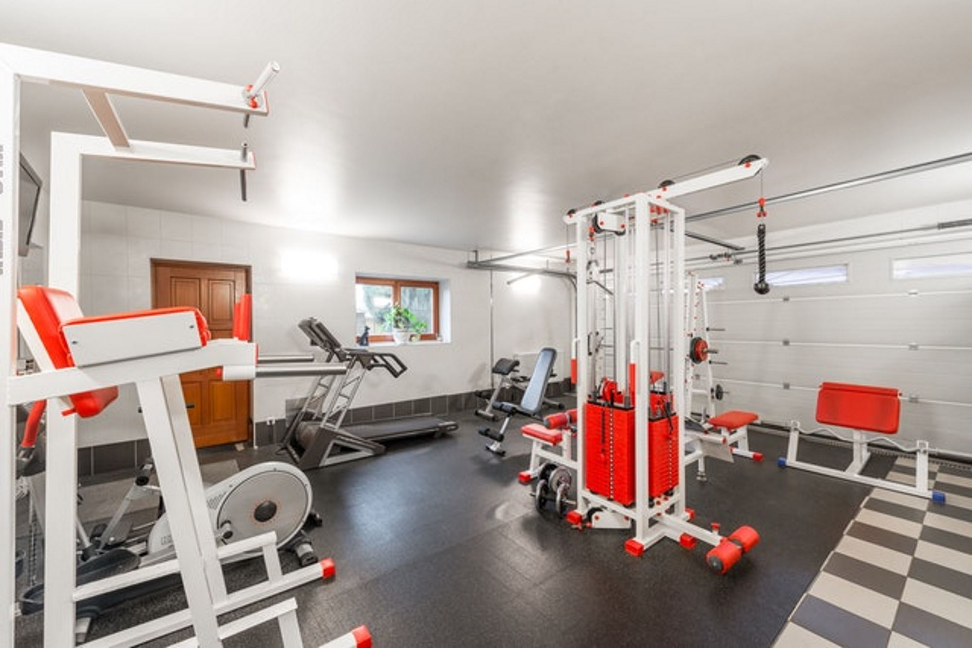 A variety of exercise and weight training equipment in a home garage gym