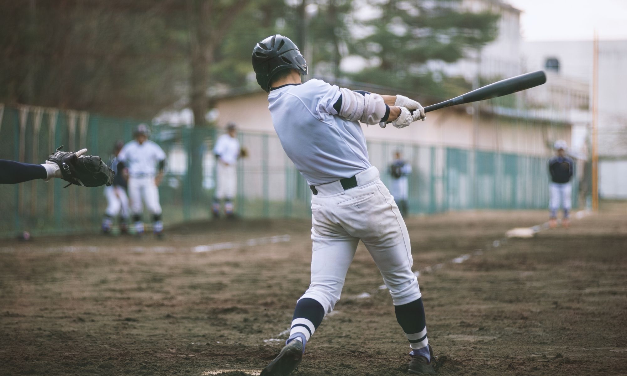 Baseball player at bat swinging at a pitch.