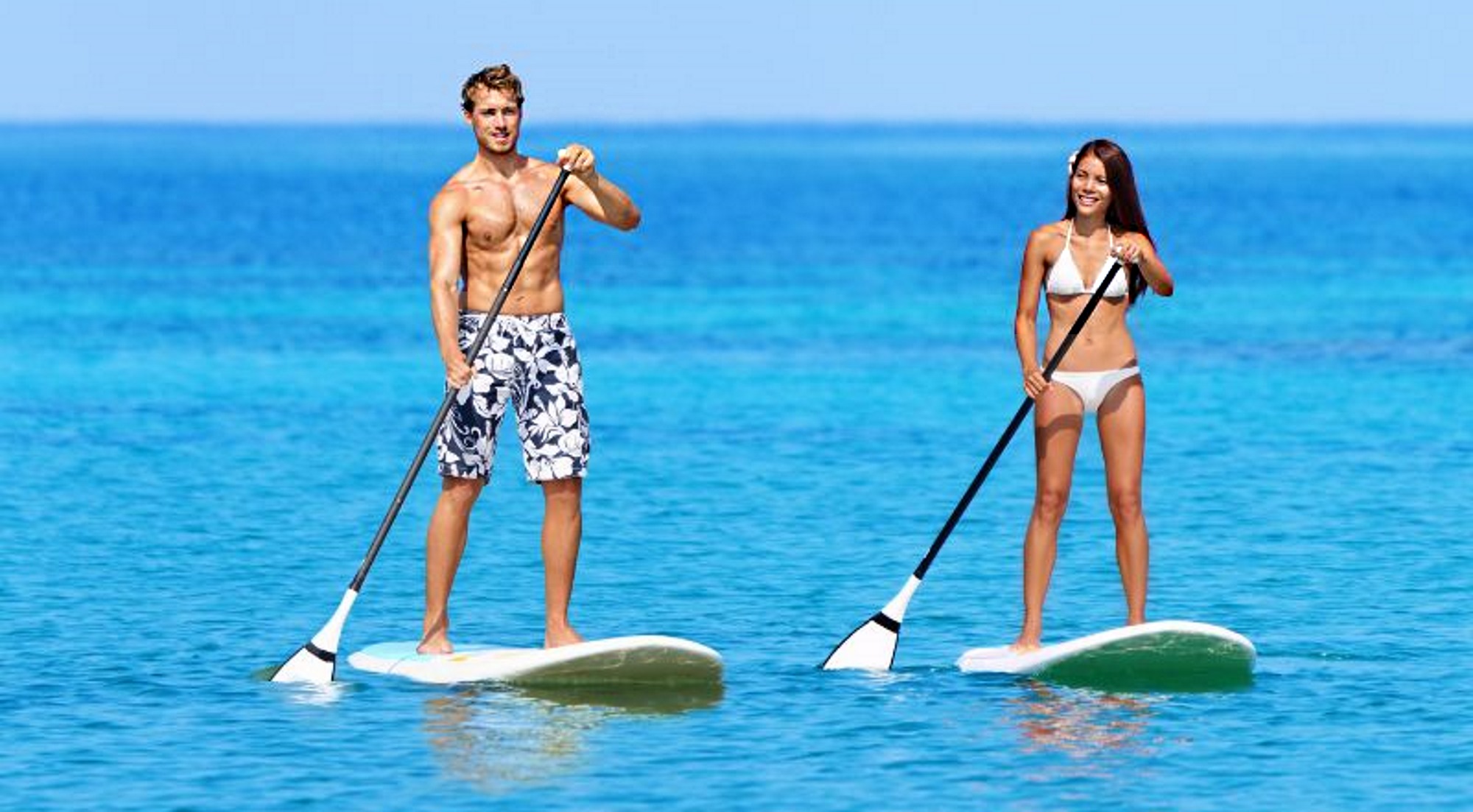 A couple enjoying the watersport of stand-up paddle boarding