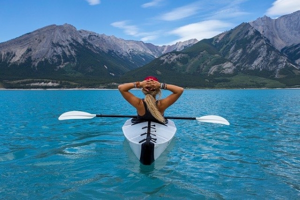 Woman kayaking on pristine blue mountain lake