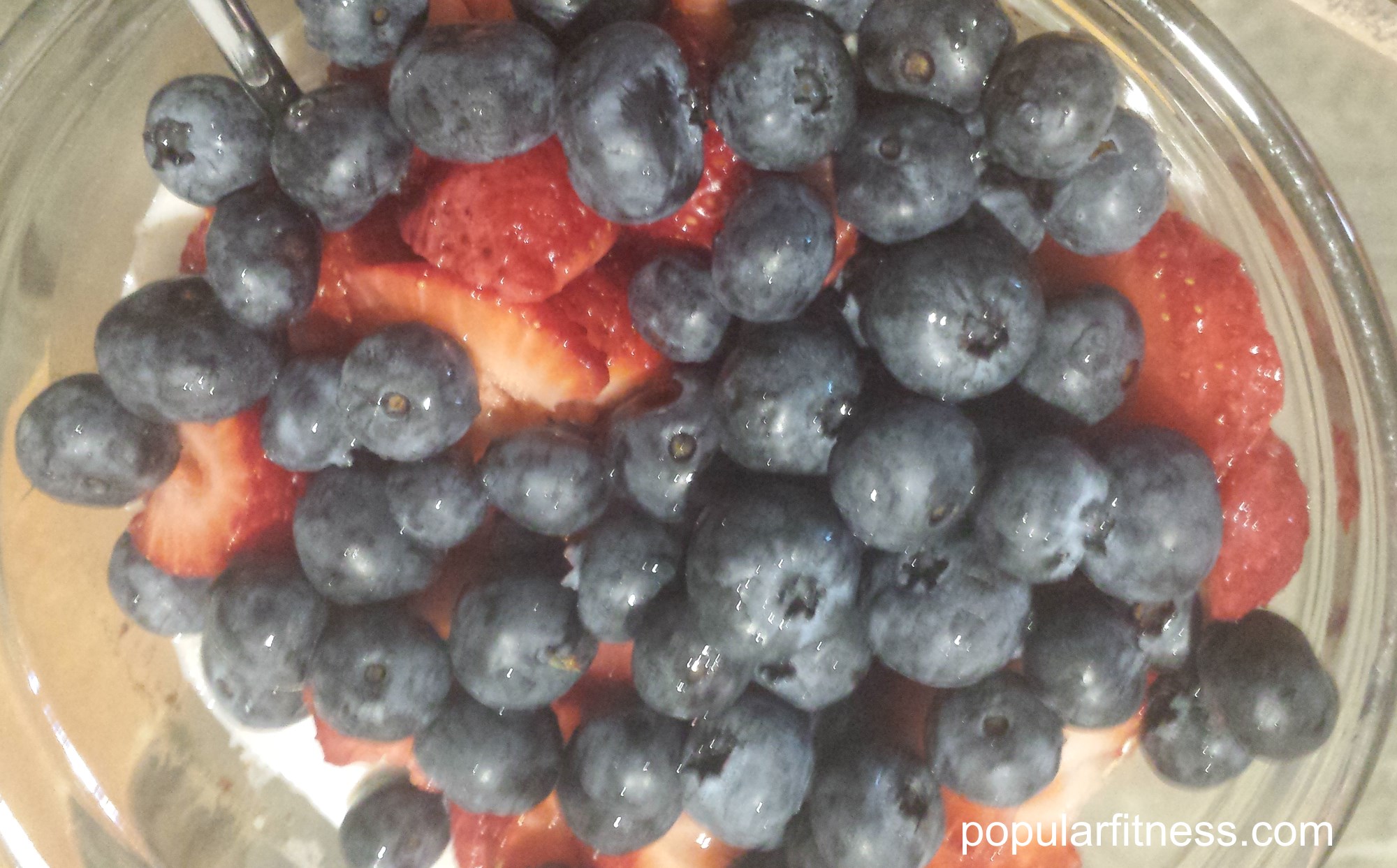 Bowl of oatmeal with fresh sliced blueberries and strawberries for breakfast