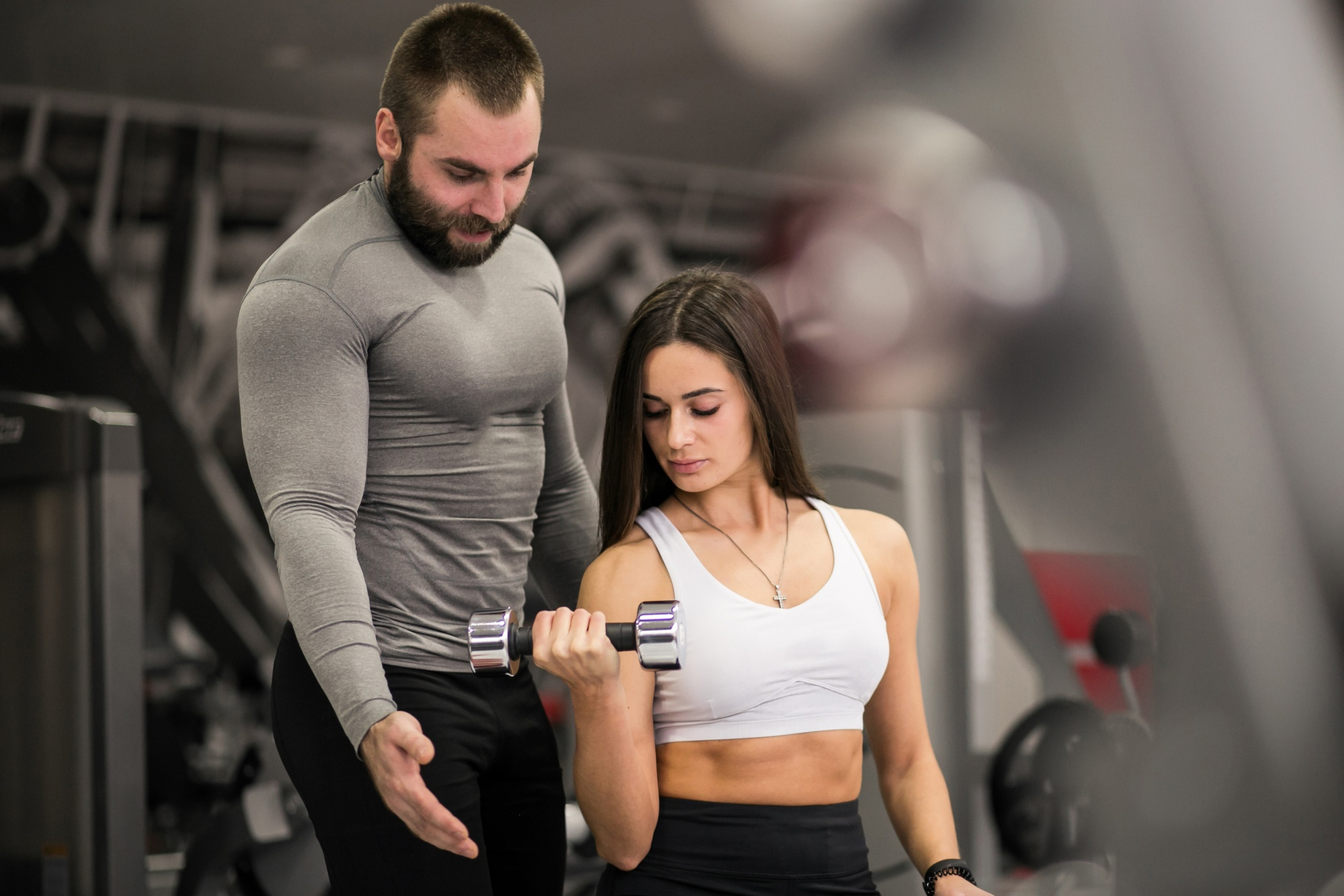 Personal trainer training woman while she does the biceps curl exercise.