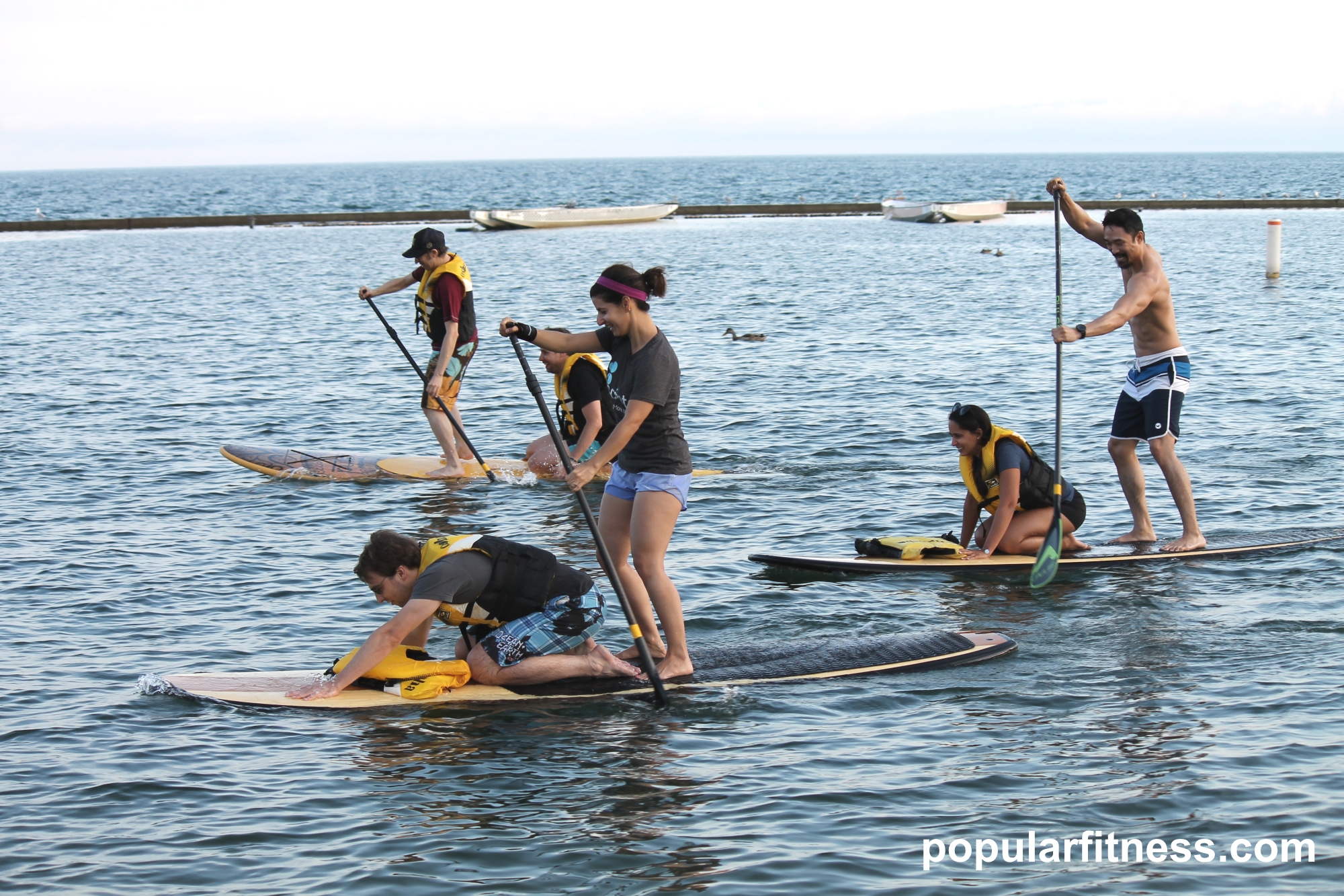 Paddle boarding on a paddleboard on the lake while standing up - photo by popular fitness