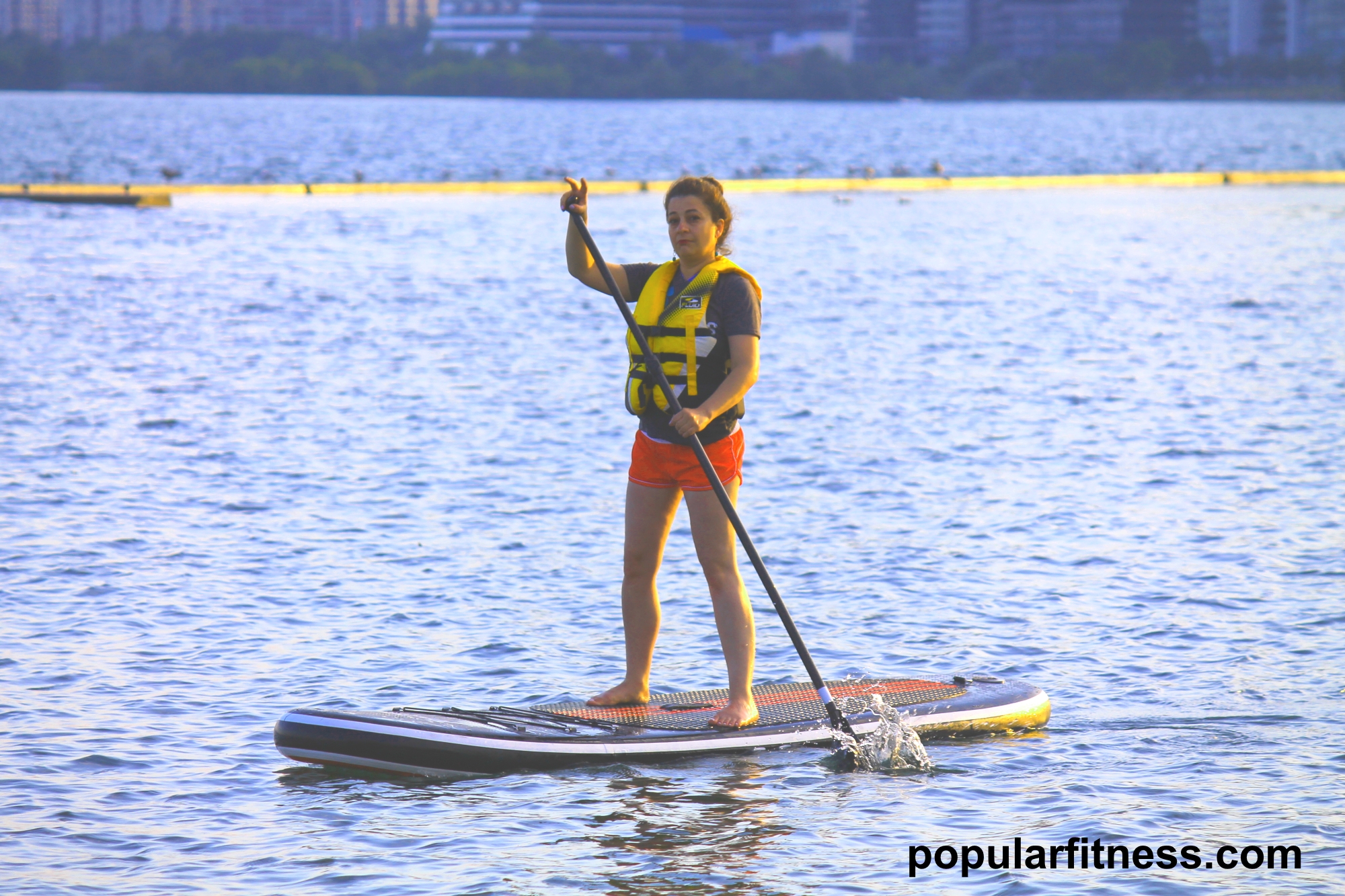 Paddle boarding on a paddleboard on the lake while standing up - photo by popular fitness