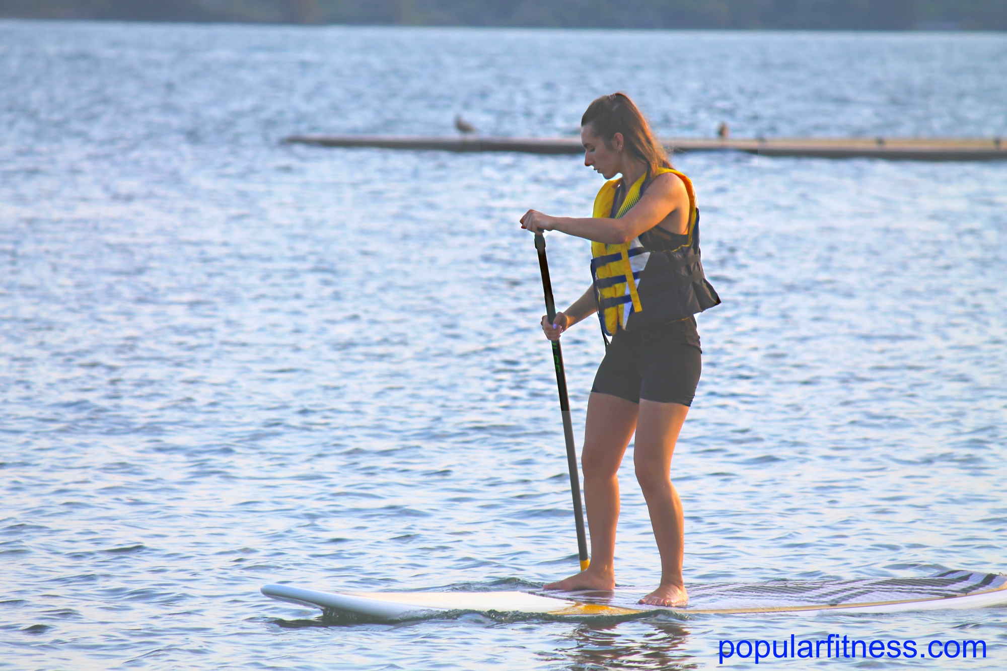 Woman enjoying the sport and exercise activity of paddleboarding by popular fitness