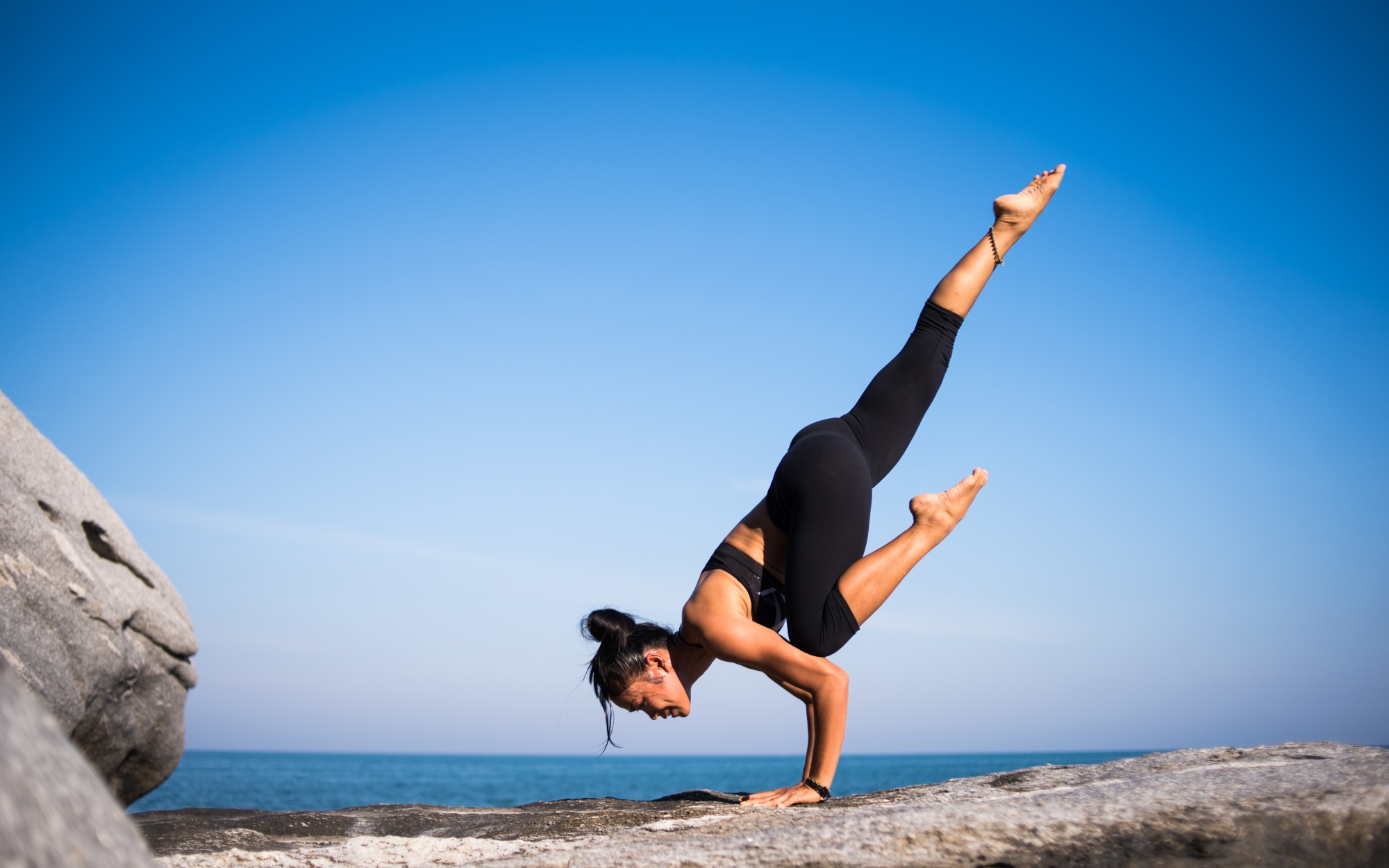 Woman doing yoga outside by the sea